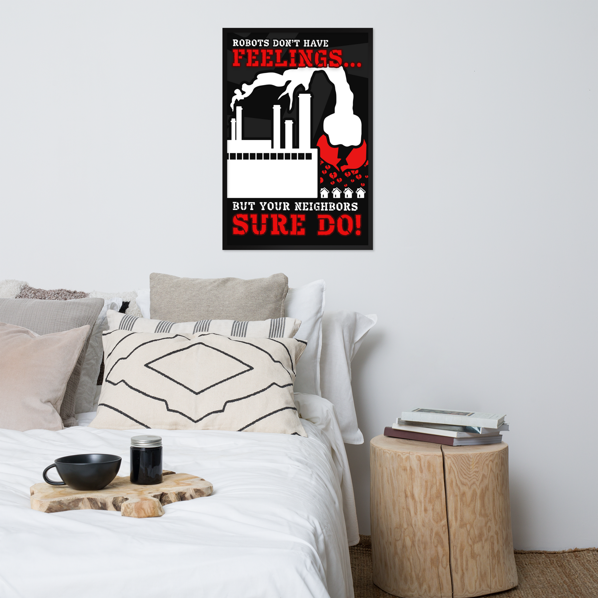 A framed wall poster with a humorous robot slogan hangs above a neatly made bed in a modern bedroom setting. The poster features a black background with white robotic factory graphics and bold red text reading 'ROBOTS DON'T HAVE FEELINGS.